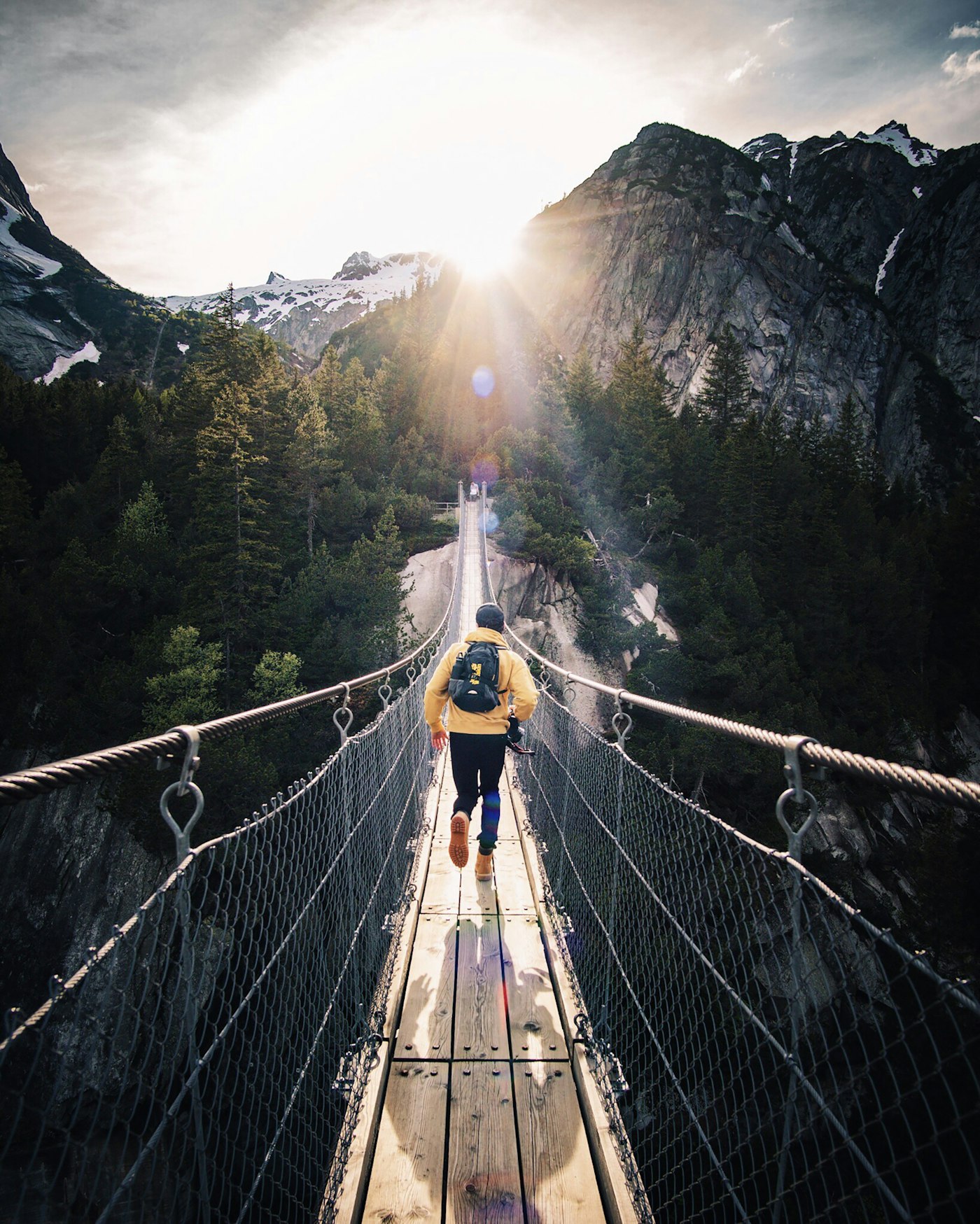 A runner crossing a guard-railed suspension bridge — moving fast because the rails are there